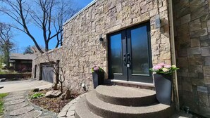 A stone building with a modern design, featuring a large glass door and a set of stone steps leading to the entrance. - Lake Gervais Retreat: Castle House - Dock and Sauna (Saint Paul)