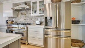A modern kitchen with stainless steel appliances, white cabinetry, and a brick backsplash. - Lake Gervais Retreat: Castle House - Dock and Sauna (Saint Paul)