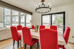 En matplats med ett träbord och röda stolar, stora fönster och en kristallkrona.