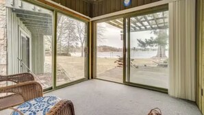 A covered patio with a view of a lake, wicker furniture, and a clock on the wall. - Lake Gervais Retreat: Castle House - Dock and Sauna (Saint Paul)