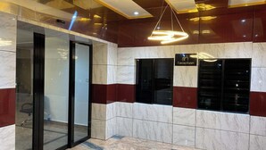 A reception area with a marble floor, a glass door entrance, and a sign indicating the reception. - Zustel Hotel (Enugu)