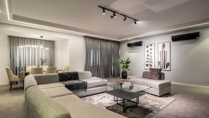 Ein modernes Wohnzimmer mit einem Ecksofa, einem Glastisch und einem Essbereich mit Stühlen und Tisch.