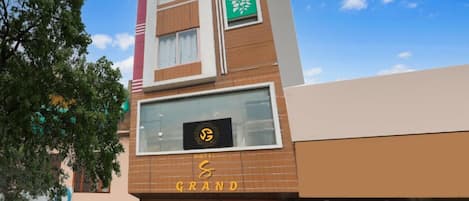 A hotel named 'Grand' with a modern architectural design, featuring a prominent logo on the facade and a green decorative panel.