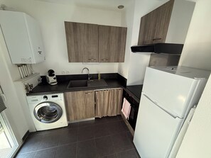 A compact kitchen with a washing machine, a sink, and a refrigerator. - Biscarrosse: Apartment in the city center, 10 min. from the ocean, 5 min. from the lake (Biscarrosse)