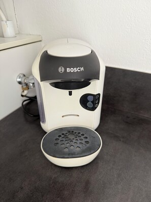 A white Bosch coffee machine with a control panel on the side, placed on a dark countertop. - Biscarrosse apartment in town center, 10 minutes from the ocean and 5 minutes from the lake (Biscarrosse)