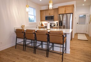 Eine moderne Küche mit Holzausbau, Edelstahlgeräten und einer Kochinsel mit Barhocker.