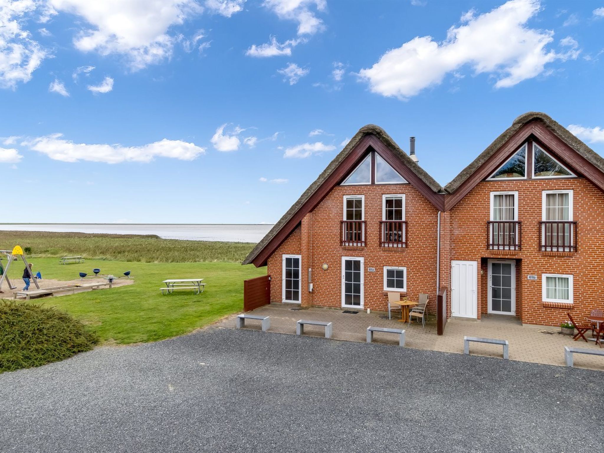 Un bâtiment à deux étages, construit en briques, avec un toit de chaume, un balcon et une vue sur la plage.