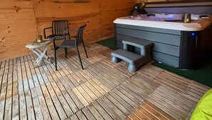 Ein gemütliches Holzhaus mit Whirlpool, Lichterketten und einer rustikalen Steinwand.