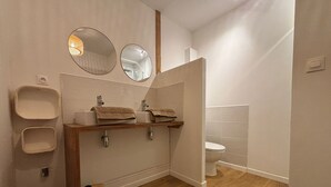 Ein modernes Badezimmer mit einem Holzlagerflächezimmer, zwei Waschbecken, einer Toilette und zwei wandmontierten Spiegeln.