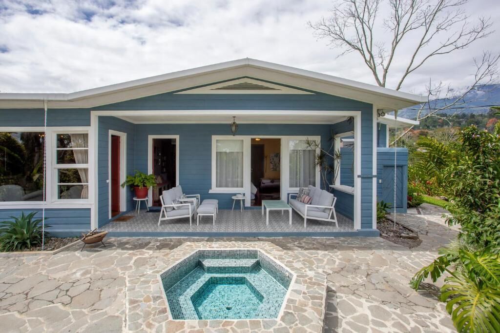 A house with a covered patio, a swimming pool, and a view of mountains.