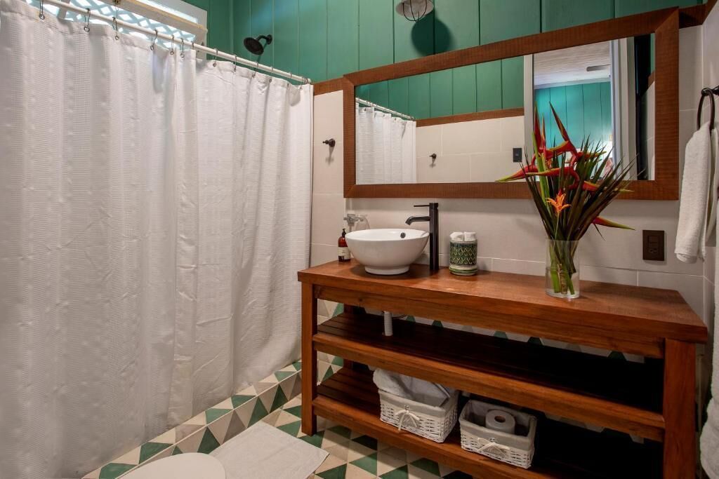 A bathroom with a white sink, a wooden vanity, a mirror, and a shower curtain.
