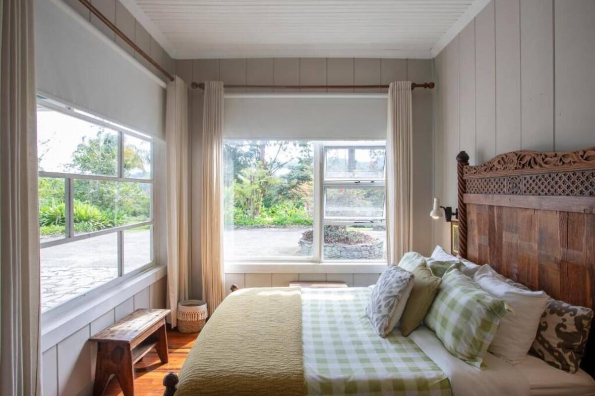 Ein Schlafzimmer mit großem Fenster, Holz-Kopfteil und einer Bank am Fenster.