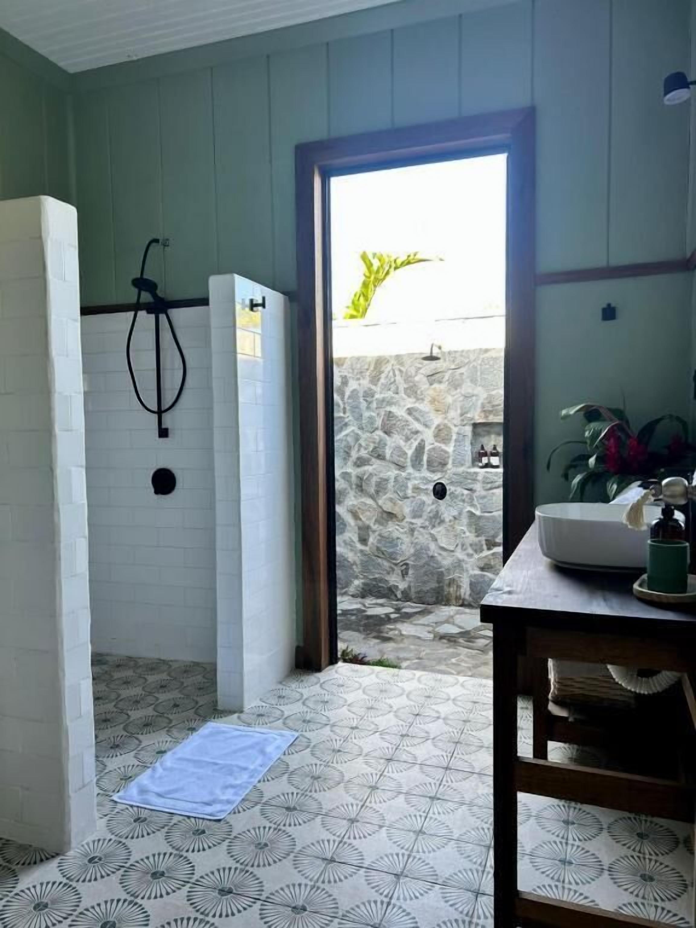 Un baño con ducha, lavamanos y pared de piedra.