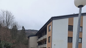 Ein mehrstöckiges Wohngebäude mit gepflastertem Innenhof, einem Metalllaternenpfahl und einer kleinen Hecke.
