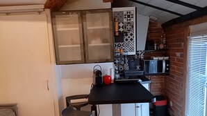 Une cuisine de taille réduite avec un plan de travail noir, un réfrigérateur blanc et un crédence décorée.