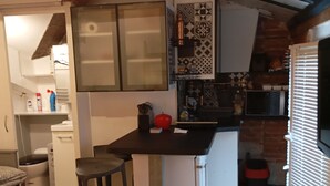 Une cuisine compacte dotée d’un îlot central, de meubles blancs et d’un crédence décorée.