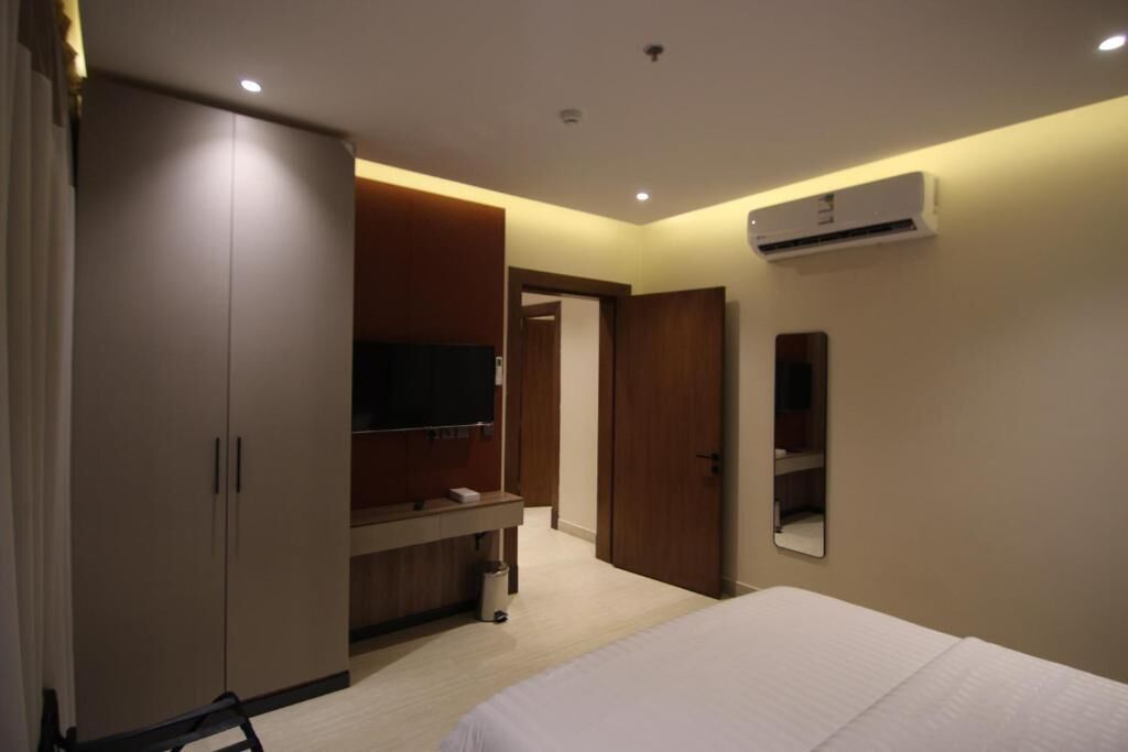Ein Hotelzimmer mit Bett, Kleiderschrank, Fernseher und Klimaanlage.
