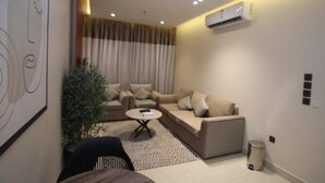 A modern living room with a sofa set, a coffee table, and a potted plant. - Aris in Apartment (Riyadh)