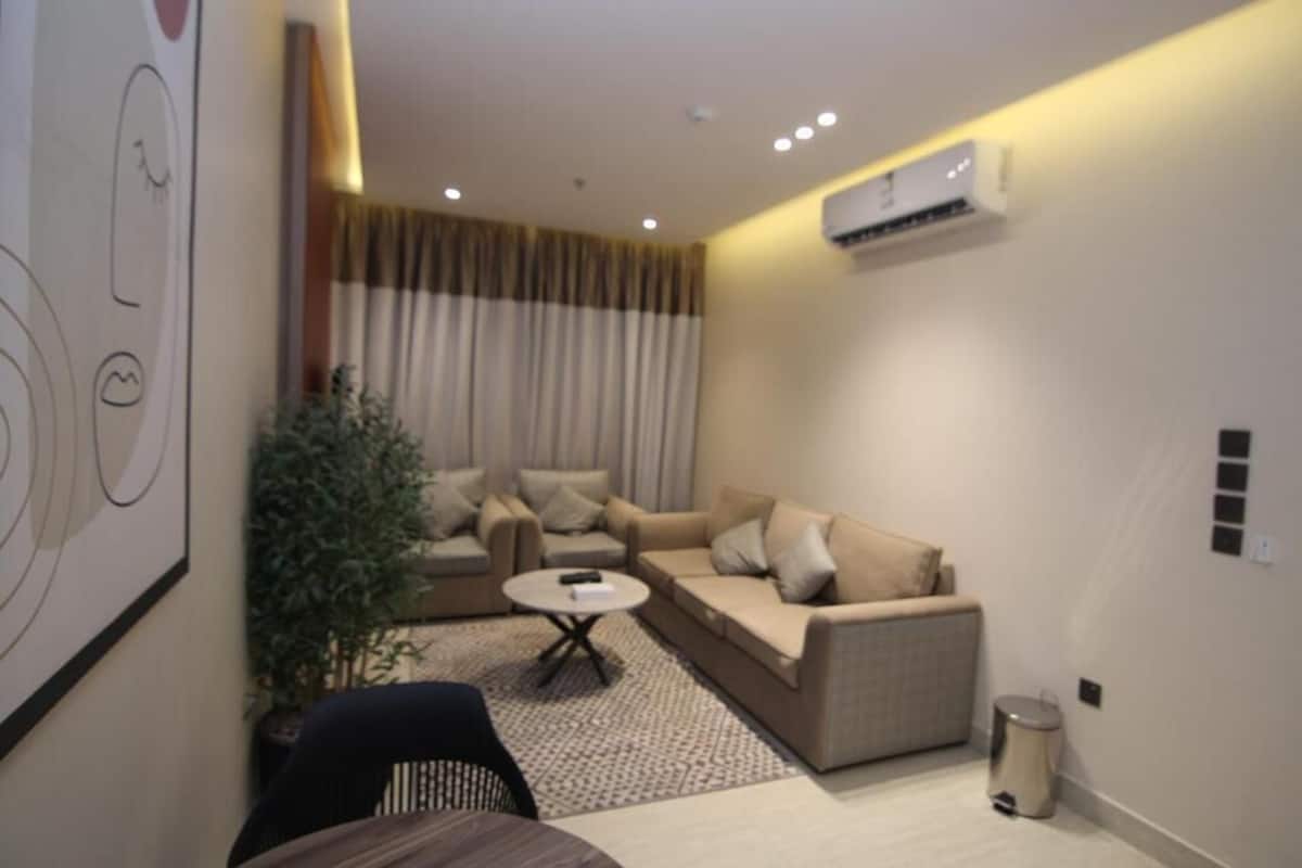 A modern living room with a sofa set, a coffee table, and a potted plant.