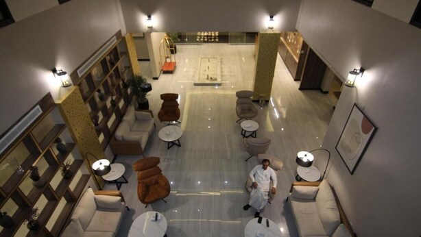 A spacious lobby with multiple seating areas, a central open space, and a staircase leading to upper floors. - Aris in Apartment (Riyadh)