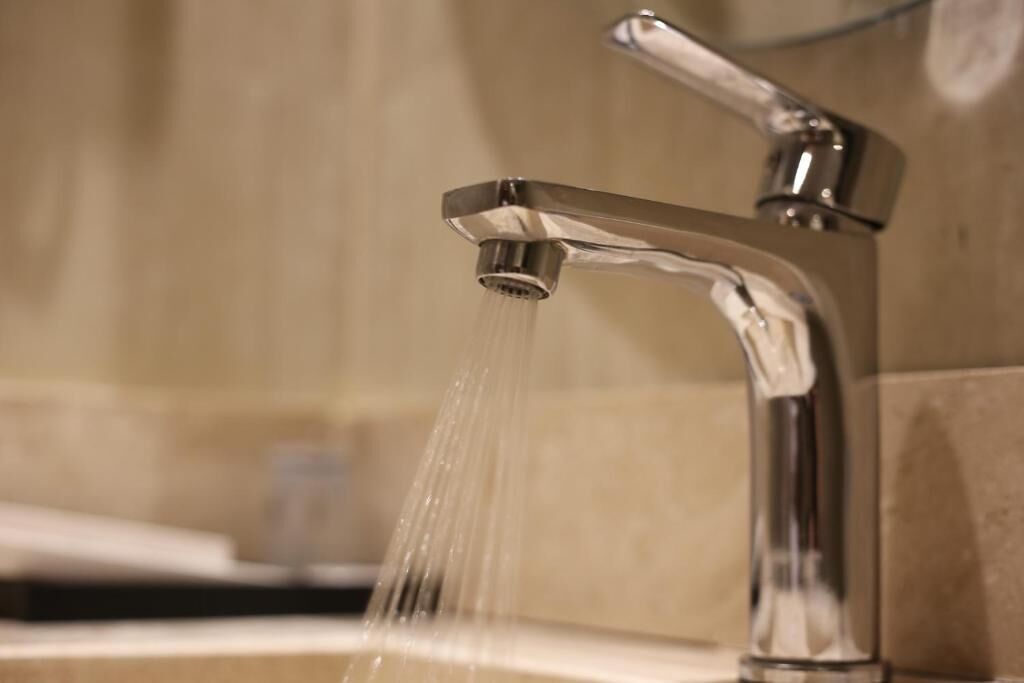 A bathroom with a chrome faucet and running water.