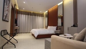 A modern hotel room with a bed, a sofa, a small table, a chair, and a large mirror. - Aris in Apartment (Riyadh)