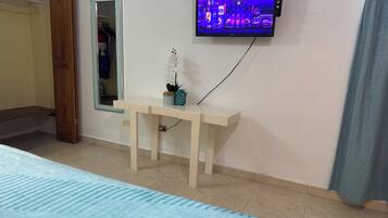 Een slaapkamer met een bed, nachtkastje, spiegel, televisietoestel en een airconditioning.