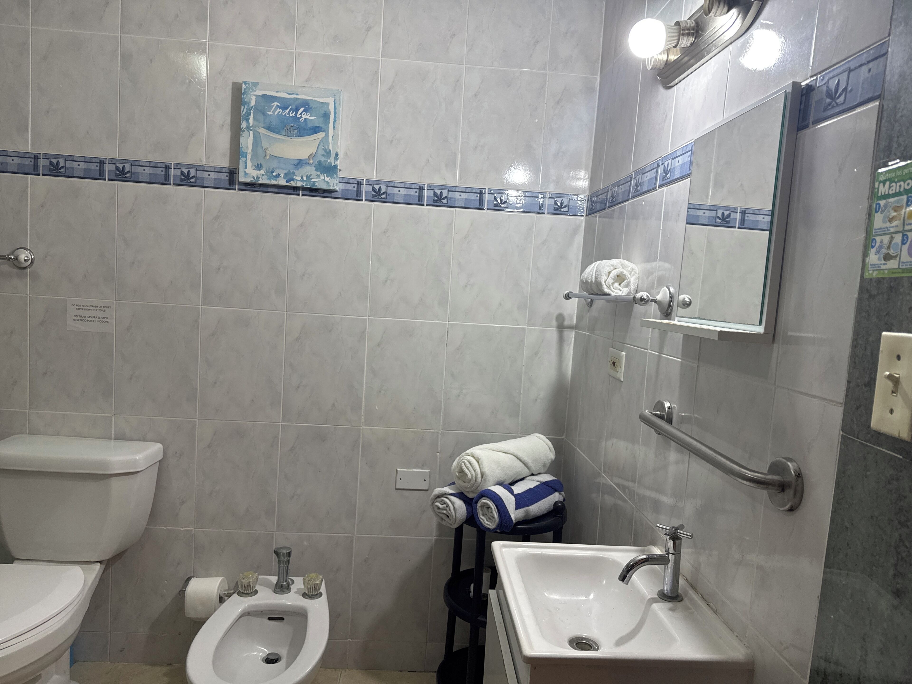 Een badkamer met toilet, bidet, wastafel en handdoekhouder.