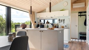 A modern kitchen with a central island, wooden ceiling, and a view of greenery outside. - "Afkar" - 900m from the sea by Interhome (Løkken)