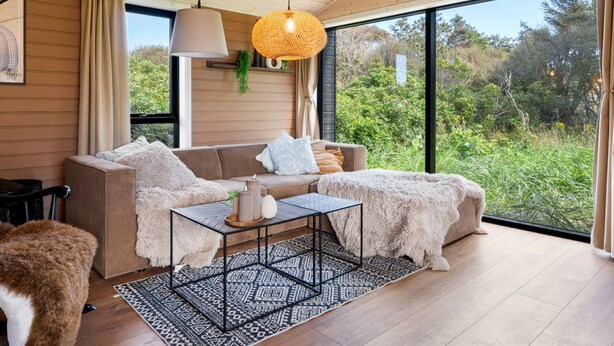 A modern living room with a wooden ceiling, a large window, a sofa, a coffee table, and a hanging light fixture. - "Afkar" - 900m from the sea by Interhome (Løkken)