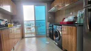 Een moderne keuken met houten kastjes, een ingebouwde wasmachine en uitzicht door de glazen deur.