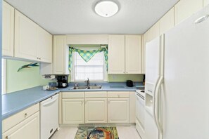 A compact kitchen with white cabinets, a sink, a coffee maker, and a refrigerator. - 3BR Dog Friendly Home- Crescent Beach- Blue Haven (North Myrtle Beach)