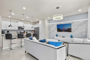 A modern kitchen with white cabinets, black bar stools, a central island, and a chandelier. - 5BD Windsor Island Resort Disney Themed (WI 3858) (Davenport)