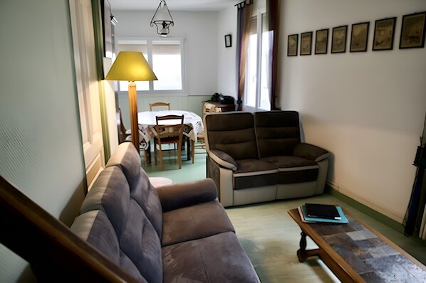 Un salon comprenant un canapé, une table basse et un coin repas avec une table et des chaises.