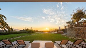 A patio with lounge chairs and a view of the sunset over a landscaped garden. - Villa Cantuccio dei Sogni (Massa Lubrense)