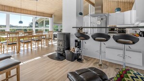 Une cuisine moderne dotée d’un îlot central, de tabourets de bar et d’un coin repas avec des chaises et une table en bois.