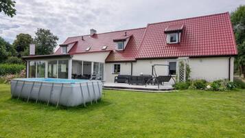 A house with a red-tiled roof, a swimming pool, and a patio area with outdoor furniture.