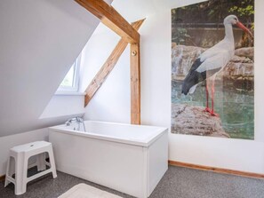 A bathroom with a white bathtub, a small white stool, and a wooden beam structure. - Comfortable House With a Swimming Pool and Sauna (gmina Dobra)
