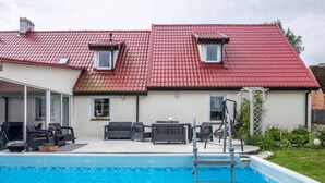 A residential property with a swimming pool, outdoor seating, and a red-tiled roof. - Comfortable House With a Swimming Pool and Sauna (gmina Dobra)