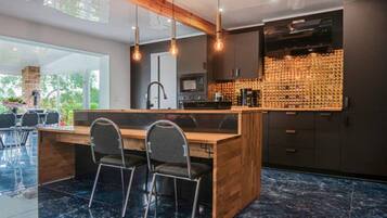 A modern kitchen with a central island, bar stools, a microwave, and a wine rack.