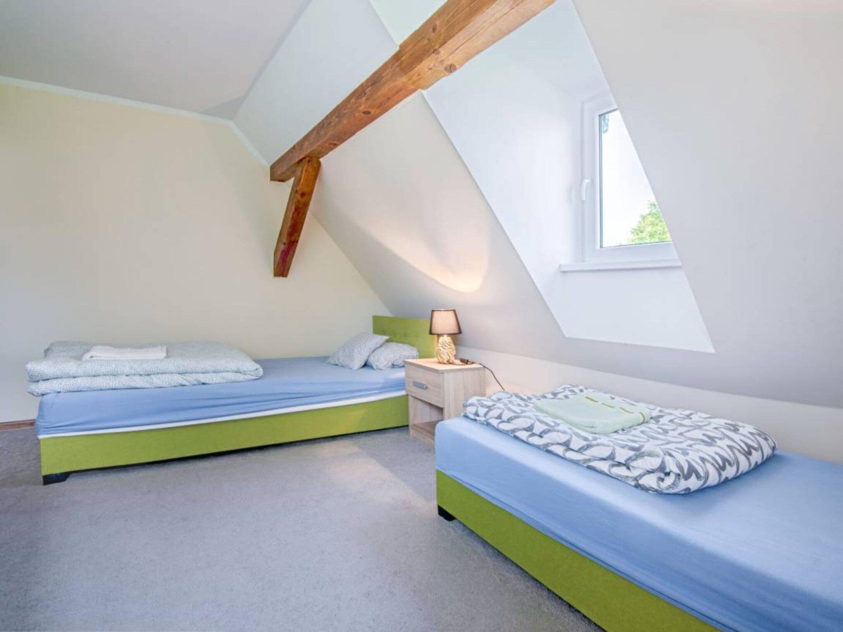 A bedroom with two beds, a window, and a sloped ceiling.