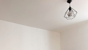 A bedroom with a bed, a nightstand, a lamp, a wooden table, and a geometric-patterned bedspread. - Spacious and quiet first floor *clim (Roquemaure)