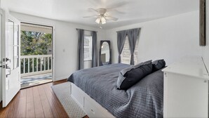 A bedroom with a bed, a ceiling fan, and a view through a door to an outdoor area.