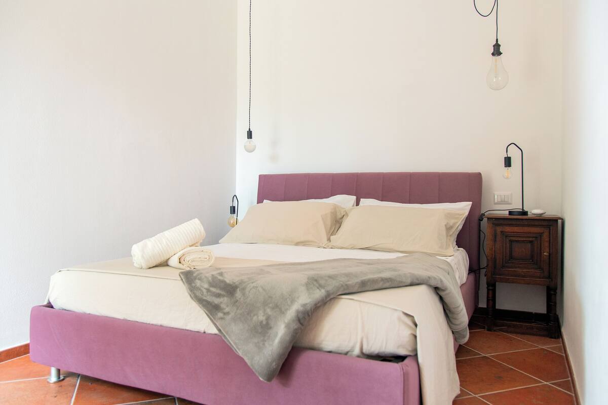 A bed with a headboard, a bedside table, and a wall-mounted light fixture.