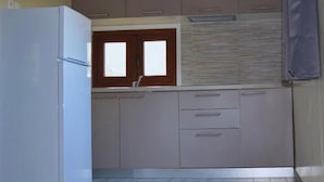 Una cocina compacta con refrigerador empotrado, muebles de madera, una ventana y piso de baldosas.