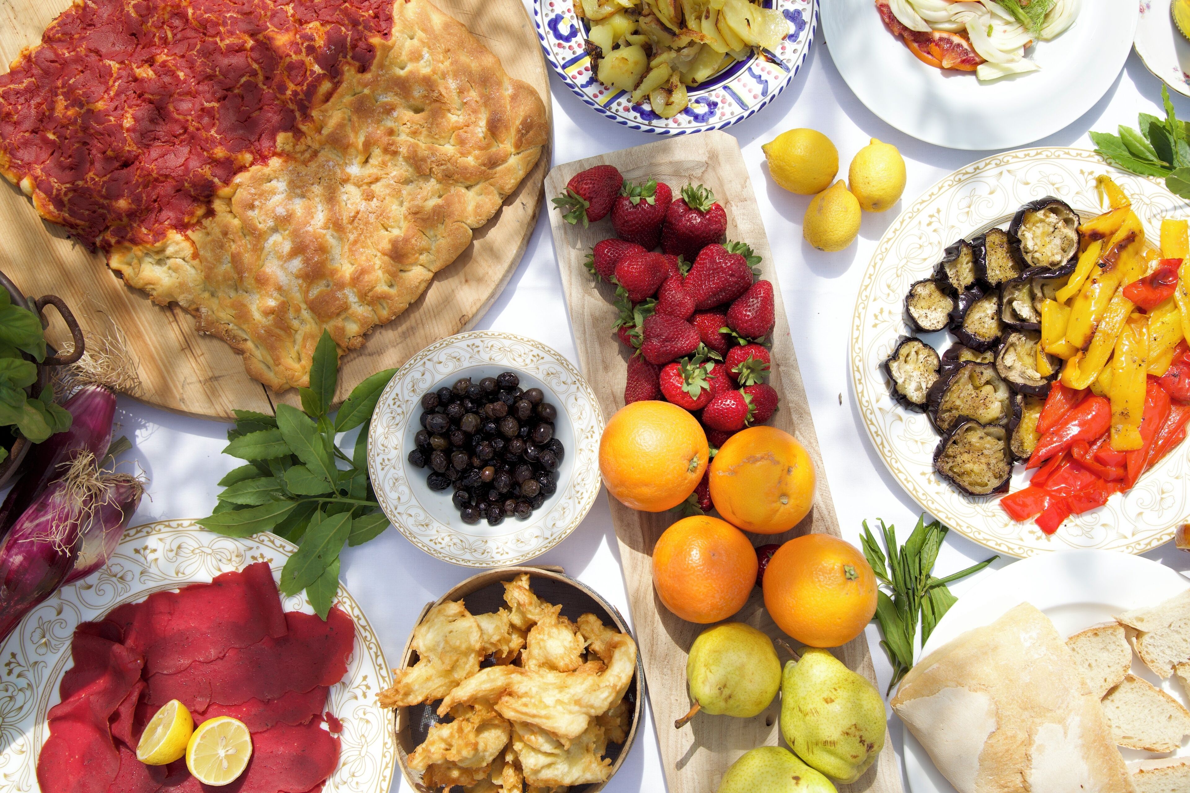 A table with various food items including a pizza, fruits, vegetables, and bread.