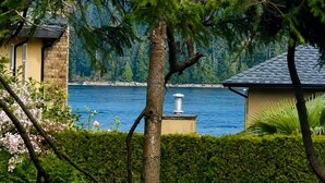 Une propriété située au bord du lac, avec un bâtiment en pierre, une cheminée et une vue sur le lac.