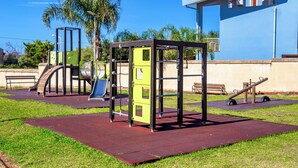 Un área de gimnasio al aire libre con equipo de ejercicio, un tobogán y un banco.