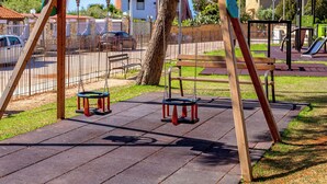Un parque infantil con columpios y una banca.