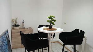 Een kleine eethoek met een ronde tafel, zwarte stoelen en een bonsai als middelpunt.